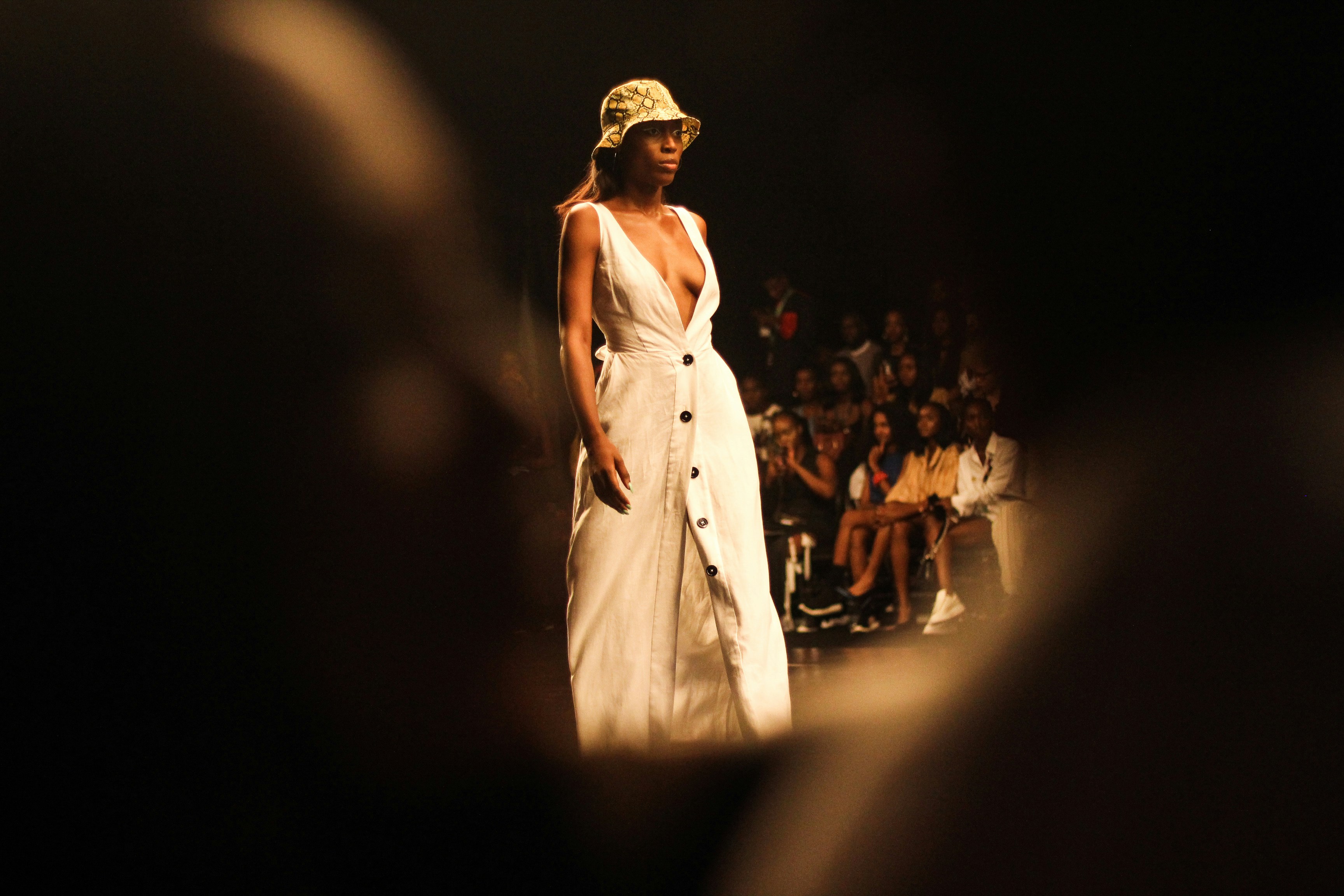 Woman in white dress and bucket hat walking down runway