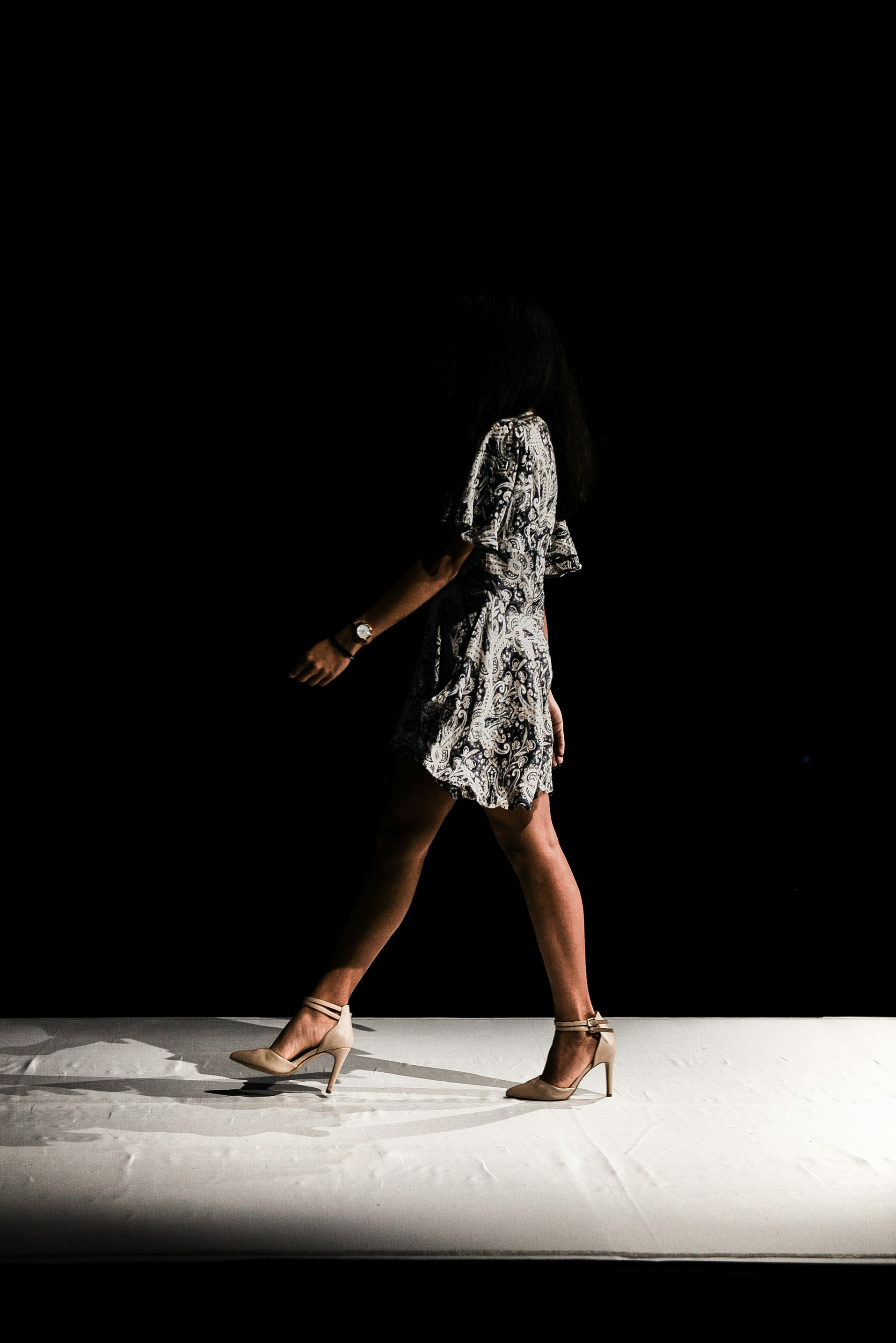 Woman in knee-length print dress walking down runway